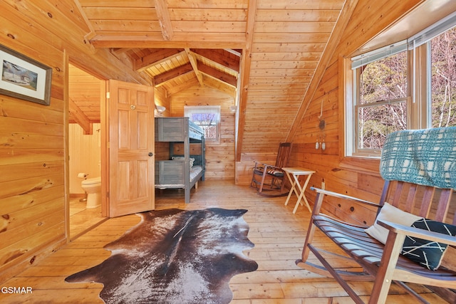 interior space featuring wood walls, hardwood / wood-style flooring, vaulted ceiling with beams, connected bathroom, and wood ceiling