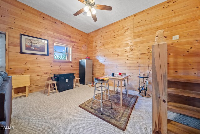 office area featuring ceiling fan, wood walls, carpet floors, and a textured ceiling