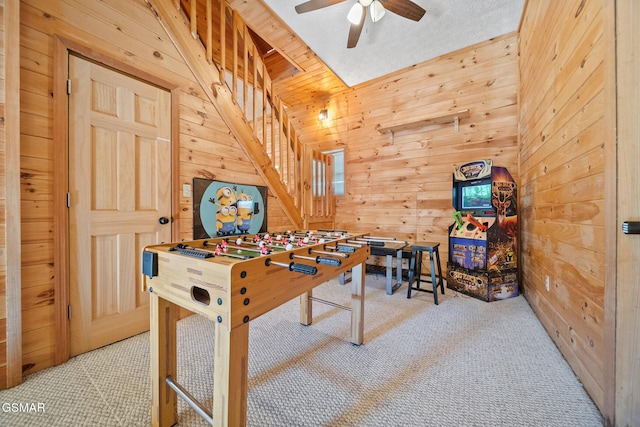 recreation room with wood walls, ceiling fan, and light carpet