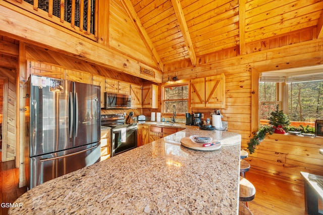 kitchen with light stone countertops, wood ceiling, stainless steel appliances, wooden walls, and sink