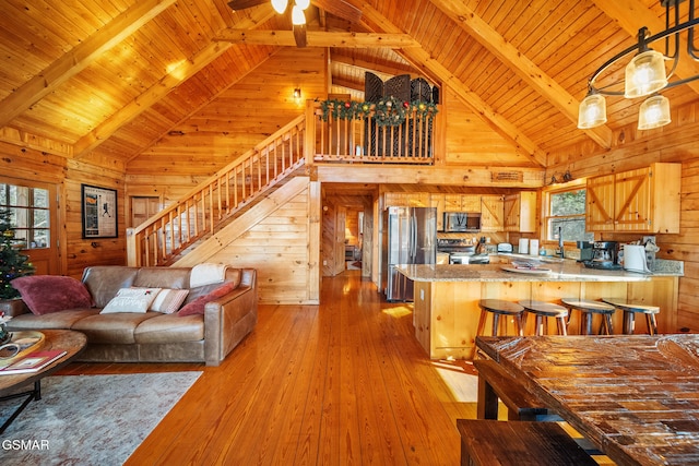 living room with beam ceiling, light hardwood / wood-style flooring, wood walls, and wood ceiling