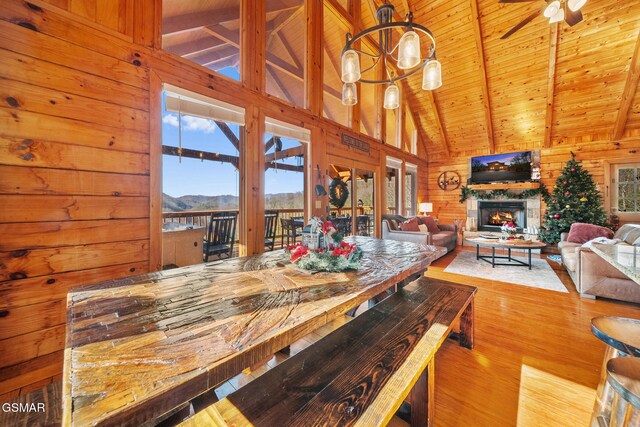 dining space featuring ceiling fan, beam ceiling, wooden ceiling, light hardwood / wood-style floors, and wood walls