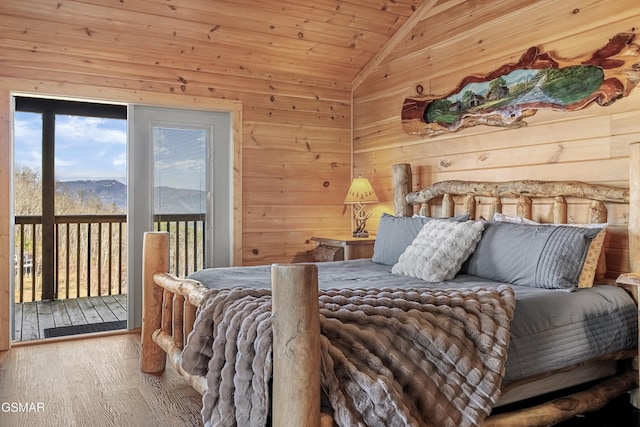 bedroom featuring lofted ceiling, access to outside, wood finished floors, and wooden walls