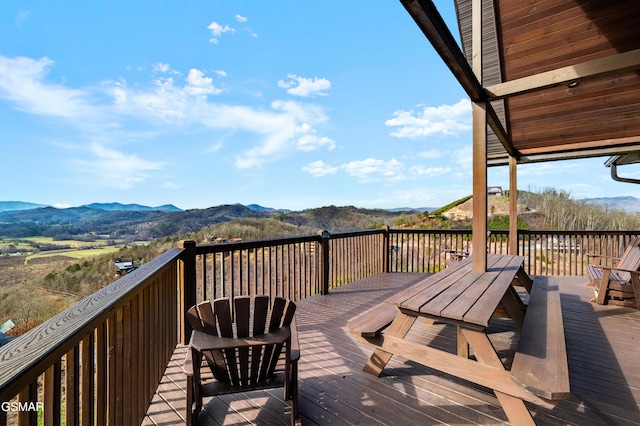 wooden deck featuring outdoor dining space and a mountain view