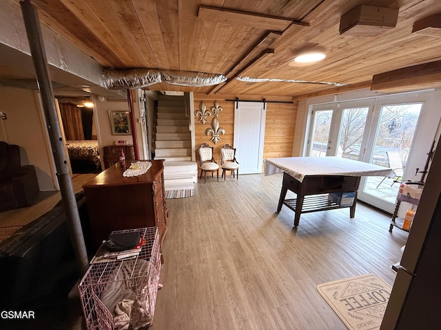 rec room featuring wooden ceiling, a barn door, wooden walls, and wood finished floors