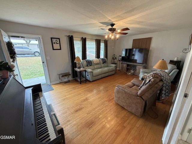 living area featuring light wood-style floors, baseboards, and a ceiling fan