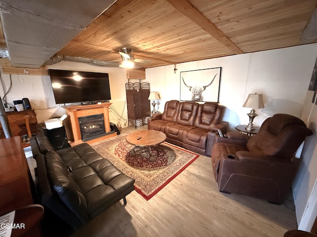 living area featuring wooden ceiling, ceiling fan, wood finished floors, and a glass covered fireplace