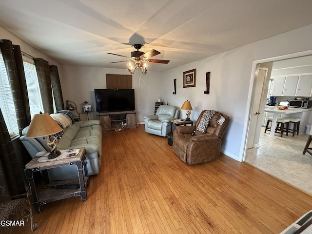 living room featuring light wood finished floors, a ceiling fan, and baseboards