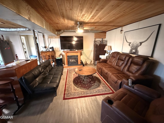 living area featuring a glass covered fireplace, wood ceiling, ceiling fan, and wood finished floors