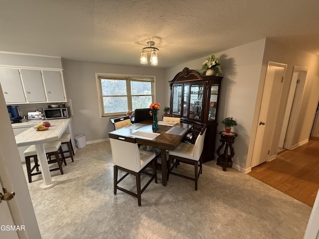 dining room with a textured ceiling and baseboards