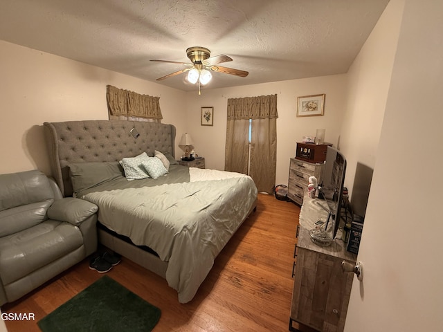 bedroom featuring a ceiling fan, a textured ceiling, and wood finished floors