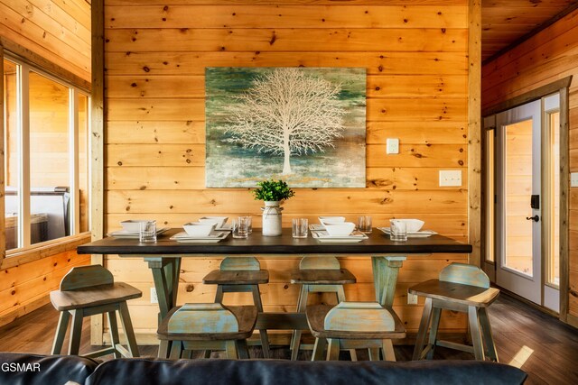 dining space featuring wooden walls and dark hardwood / wood-style flooring