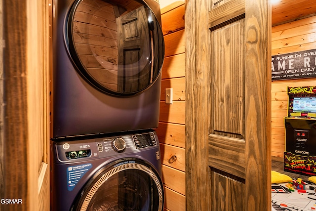 laundry room featuring wooden walls and stacked washer / drying machine