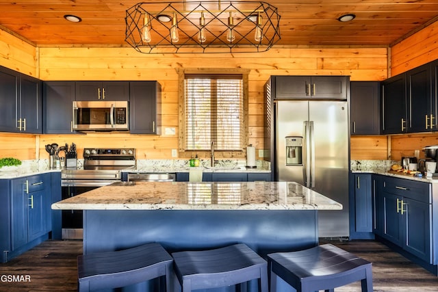 kitchen with wood walls, sink, wooden ceiling, and stainless steel appliances