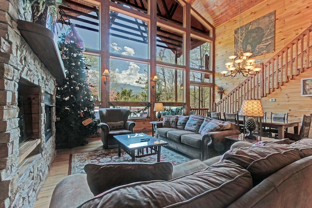 living room featuring high vaulted ceiling, wooden ceiling, a chandelier, hardwood / wood-style floors, and a stone fireplace