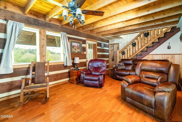 living area featuring beam ceiling, light wood finished floors, stairway, wood walls, and wooden ceiling