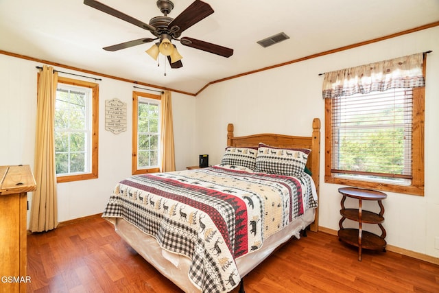 bedroom featuring crown molding, visible vents, ceiling fan, and wood finished floors