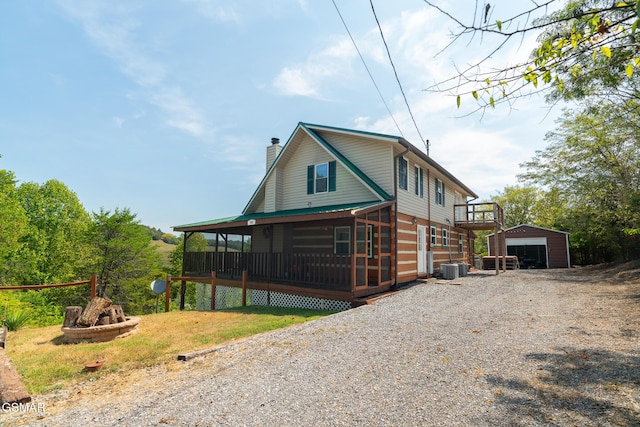 view of front of home with an outbuilding, a detached garage, a chimney, central AC unit, and driveway