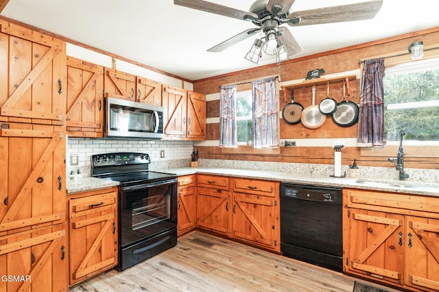 kitchen featuring light wood-type flooring, black appliances, a wealth of natural light, and a sink