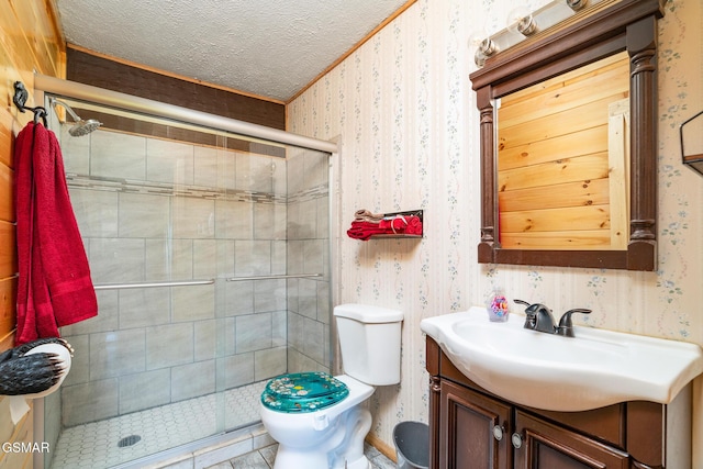 full bathroom with wallpapered walls, a stall shower, toilet, a textured ceiling, and vanity
