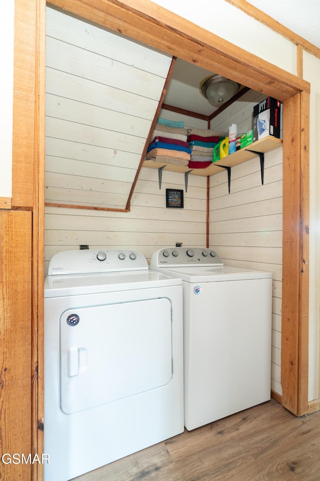 laundry room featuring light wood-style floors, laundry area, independent washer and dryer, and wood walls