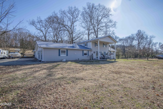 back of property featuring covered porch and a lawn