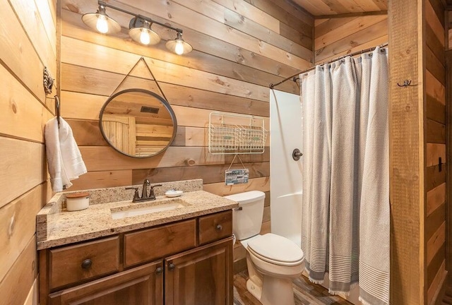 bathroom with vanity, wooden walls, a shower with shower curtain, and toilet