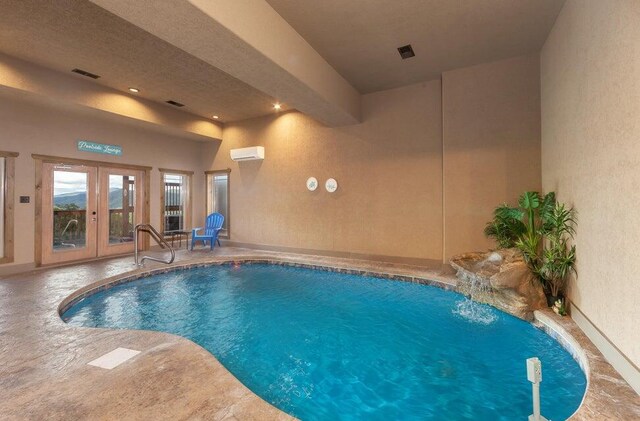 view of swimming pool with pool water feature, a wall unit AC, and french doors