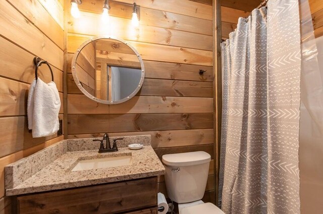 bathroom featuring wooden walls, vanity, a shower with shower curtain, and toilet