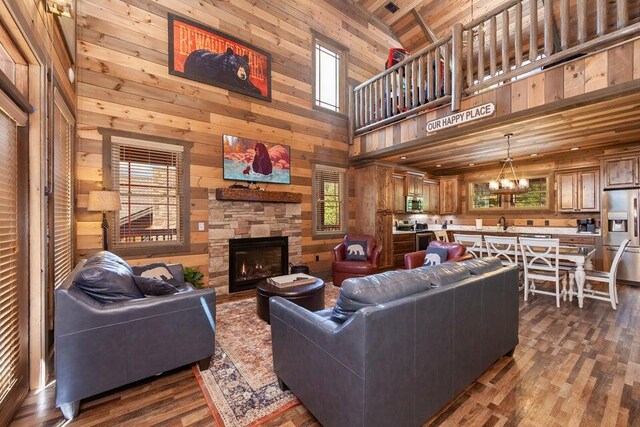 living room featuring wooden ceiling, dark hardwood / wood-style flooring, high vaulted ceiling, a chandelier, and a fireplace