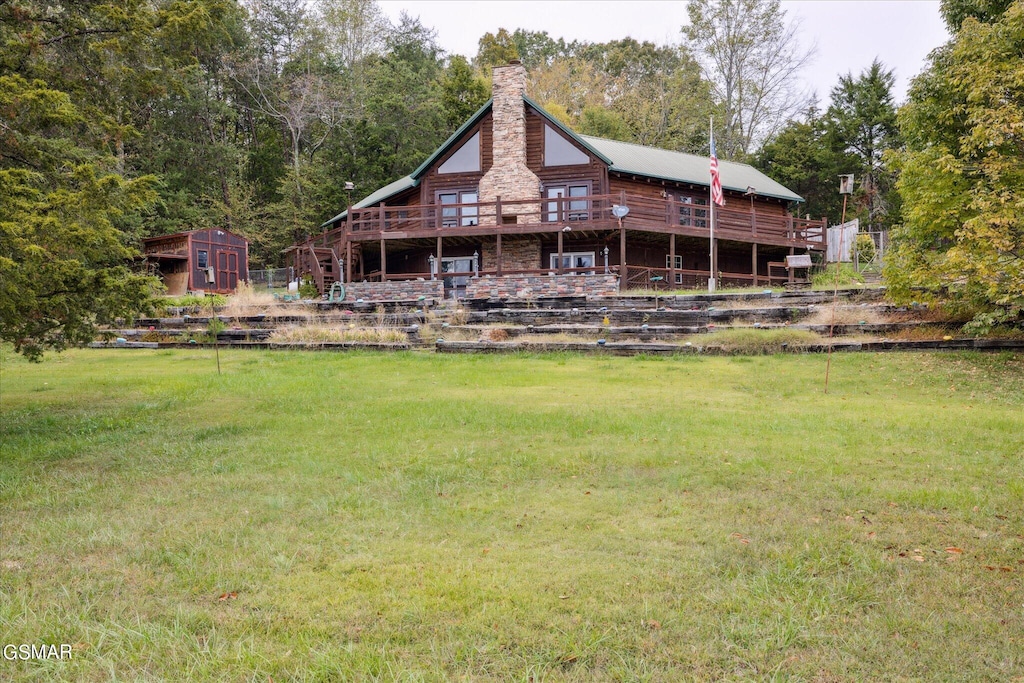 back of house with a shed, a deck, and a lawn