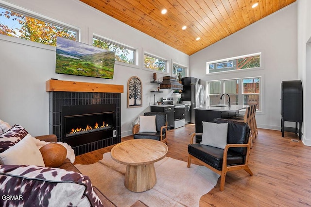 living room with high vaulted ceiling, sink, hardwood / wood-style flooring, wood ceiling, and a tiled fireplace