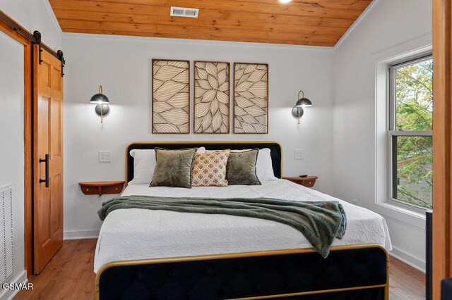 bedroom featuring lofted ceiling, a barn door, wood-type flooring, and wooden ceiling