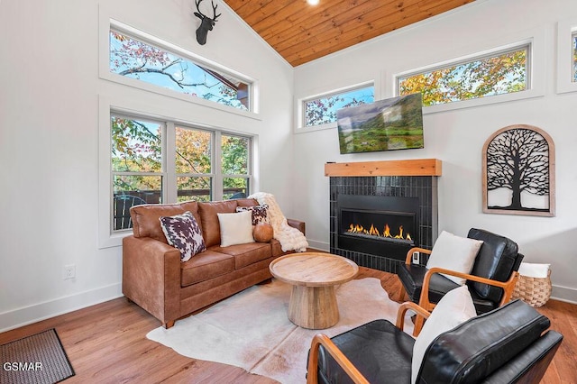 living room with a tile fireplace, light hardwood / wood-style flooring, high vaulted ceiling, and wood ceiling