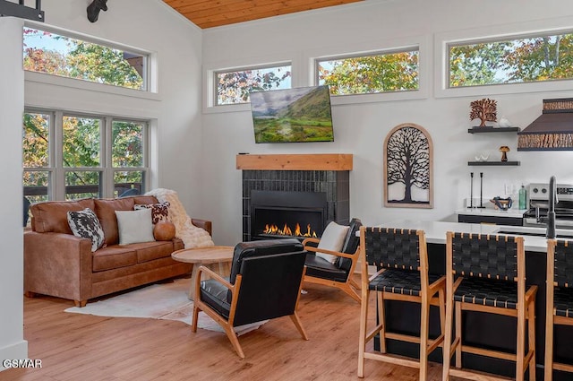 living room with sink, light hardwood / wood-style flooring, wooden ceiling, a fireplace, and lofted ceiling