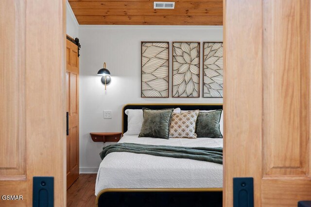 bedroom featuring hardwood / wood-style flooring, a barn door, and wooden ceiling