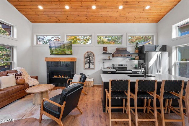 living room featuring lofted ceiling, light wood-type flooring, wooden ceiling, and sink