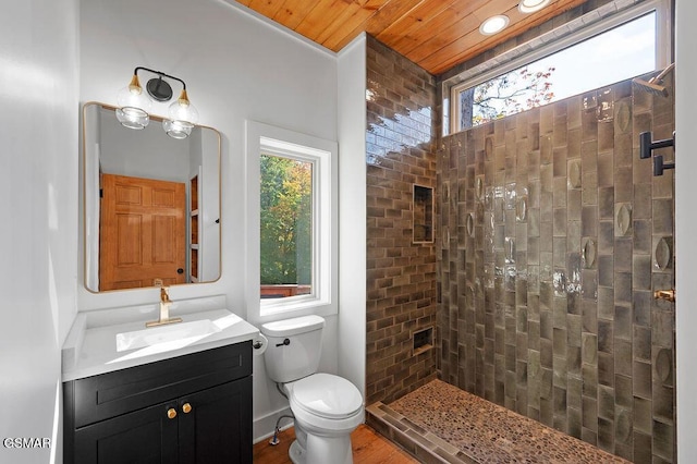 bathroom with vanity, toilet, a tile shower, and wood ceiling