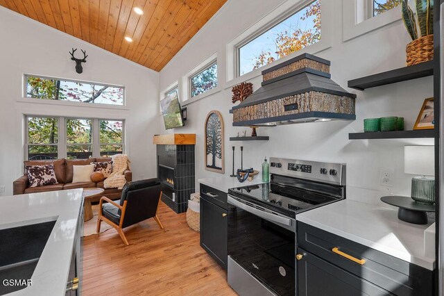 kitchen with custom exhaust hood, a tile fireplace, electric range, wooden ceiling, and light hardwood / wood-style floors