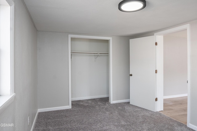 unfurnished bedroom with carpet floors, a closet, and baseboards