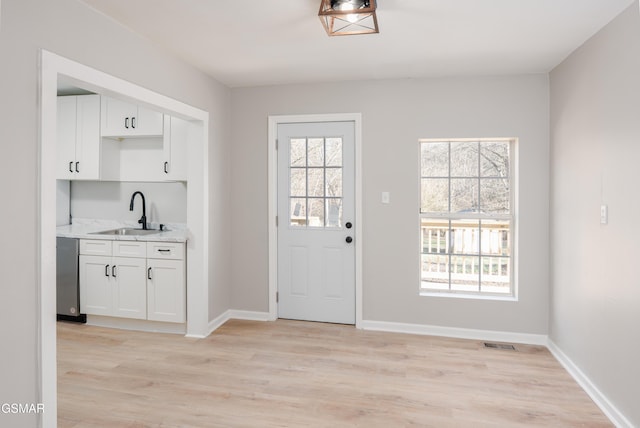 entryway featuring light wood finished floors, a sink, visible vents, and a healthy amount of sunlight