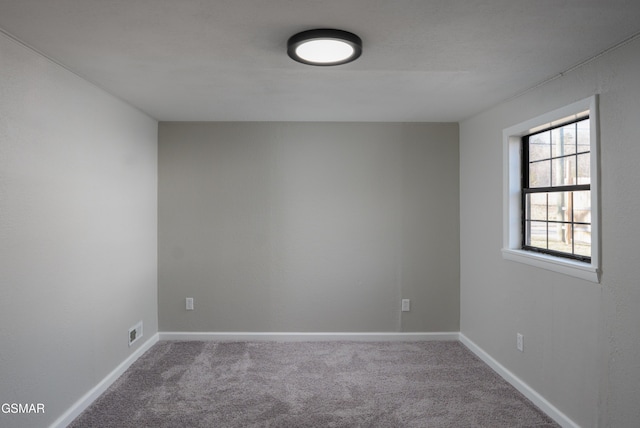 carpeted spare room featuring visible vents and baseboards