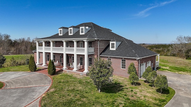 view of front of property with covered porch, a balcony, a garage, and a front yard