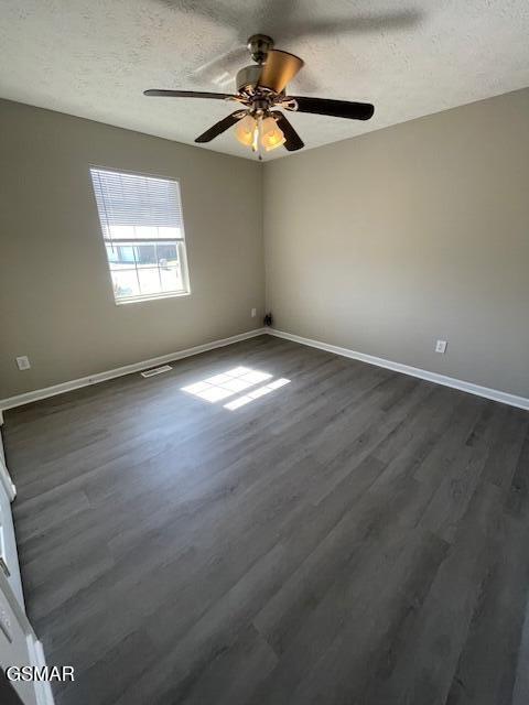 spare room featuring dark wood-style floors, a textured ceiling, and baseboards