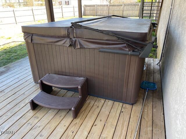 wooden deck with a hot tub and fence