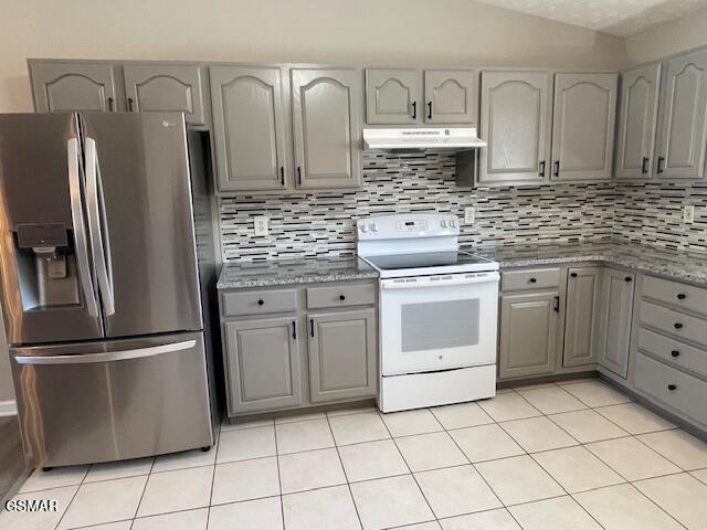 kitchen with white electric stove, gray cabinets, stainless steel fridge, and under cabinet range hood