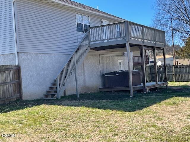 rear view of house with a hot tub, a lawn, stairs, fence, and a deck