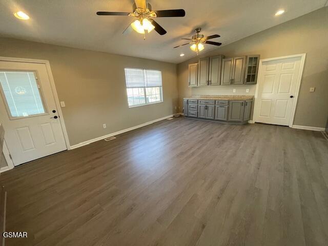 interior space featuring dark wood finished floors, recessed lighting, gray cabinetry, vaulted ceiling, and baseboards