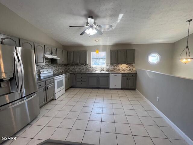 kitchen featuring light tile patterned flooring, gray cabinetry, white appliances, backsplash, and range hood