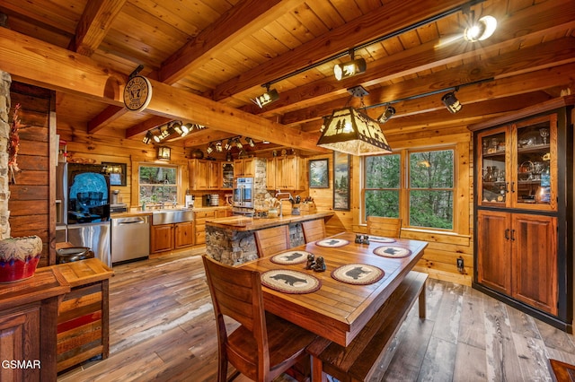 dining space featuring beam ceiling, wooden walls, and light wood-style flooring